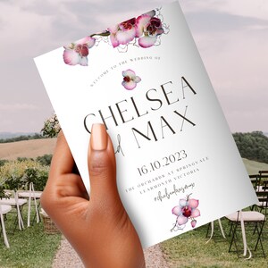 May include: Wedding program with pink orchid floral design. The program reads "Welcome to the wedding of Chelsea and Max" with the date "16.10.2023" and the location "The Orchards at Springvale, Learmonth Victoria".