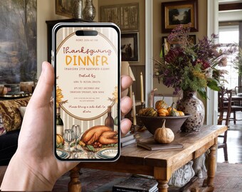 May include: A smartphone screen shows a Thanksgiving Dinner invitation. The invitation includes a turkey, wine, and a table setting. The text reads "Thanksgiving Dinner" with the date, time, and location. The phone is held in front of a table with pumpkins and a floral arrangement.