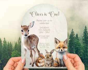 May include: A woodland-themed first birthday party invitation with a fawn, fox, squirrel, and rabbit. The invitation is in the shape of an arch and has a light green background with a woodgrain texture. The text on the invitation reads "Oliver is One!" and includes the date, time, and location of the party. RSVP information is also included.