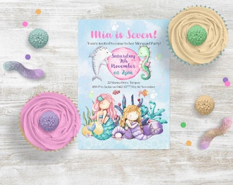 May include: A blue and pink invitation card with a mermaid theme. The card says "Mia is Seven!" and invites guests to a mermaid party on Saturday, 9th November at 2pm. The card also includes a dolphin, a seahorse, and two mermaids.