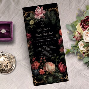 May include: A wedding invitation with floral design, featuring the names Sophie London and Charles Sutherland. The invitation is black with pink and red flowers, a ring in a purple box, a silver compact, and a bouquet of flowers.