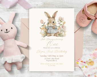 Puede incluir: Una tarjeta de invitación rosa y blanca con una ilustración de acuarela de un conejito con una camisa azul. El texto en la tarjeta dice "Sovie Bunny is turning One. Please join us to celebrate Eliza's First Birthday. Sunday 14th May at 2pm. 22 East Lake Road, Paynesville, IL. RSVP to Katie on (123) 456 7890 by 5th May."