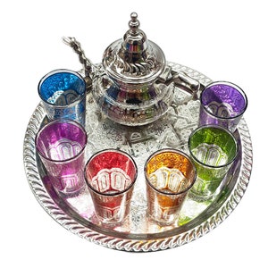 Juego de té tradicional marroquí con teteras decorativas, vasos y hojas de  menta.