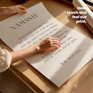 Puede incluir: Un p&oacute;ster blanco con el texto "NAMASTE" en letras grandes y en negrita en la parte superior. El p&oacute;ster presenta una cita en alem&aacute;n, "Meine Seele chrt. Deine Sede Ich ehre den Ort in Dir, an dem sich das ganze Universum befindet. Ich ehre das Licht, die Liebe. Schonheit. Veisheit in Dir. Indem wir die Dinge teilen, sind wir vereint, sind wir gleich, WIR SIND EINS." El p&oacute;ster est&aacute; siendo sostenido por una mano.