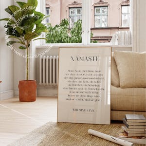 Puede incluir: Un p&oacute;ster beige con un marco negro y la palabra "NAMASTE" en letras grandes y negritas. El p&oacute;ster presenta una cita en alem&aacute;n sobre el alma y el universo.