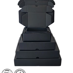 May include: A stack of black corrugated cardboard boxes of varying sizes, some open and some closed. The boxes are arranged in a pyramid shape, with the largest at the bottom and the smallest at the top. The boxes are all the same color and have a matte finish.