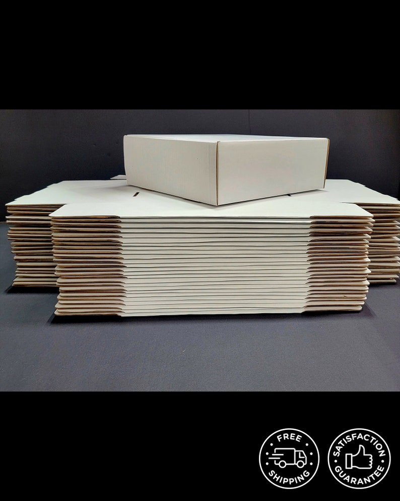 May include: A stack of flat, white cardboard shipping boxes with one assembled box resting on top. The boxes are constructed from plain, matte white paperboard with visible corrugated edges, designed for packaging and mailing various items.