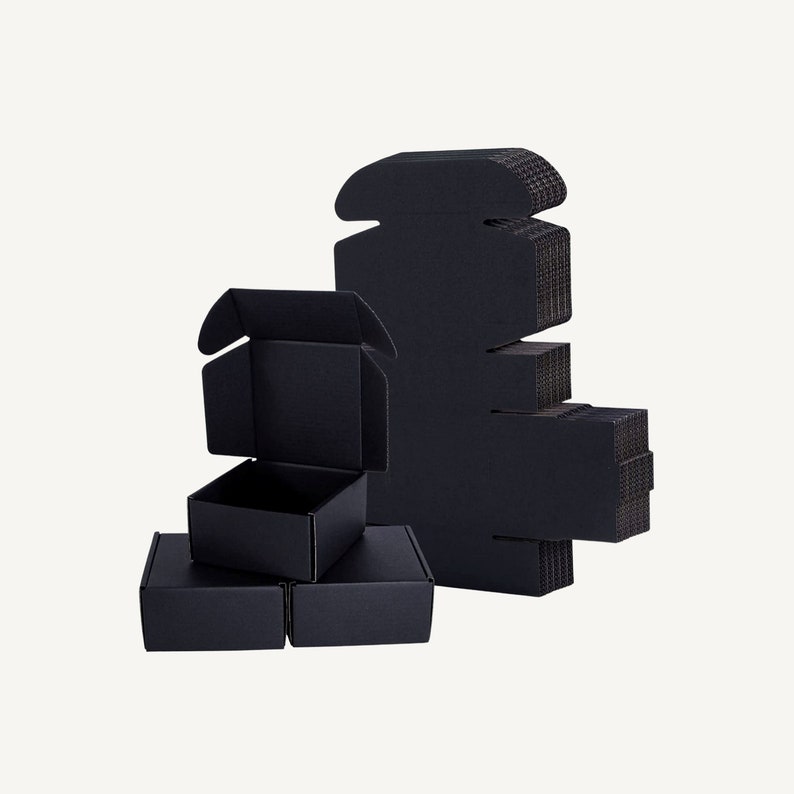 May include: Several black cardboard boxes are displayed against a white background. Some boxes are assembled, while others are flat and ready to be folded. The boxes are various sizes and shapes, suitable for packaging and shipping.