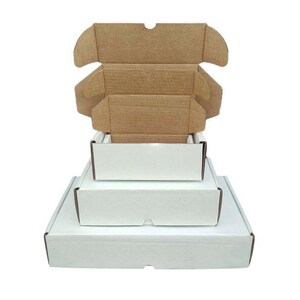May include: A stack of three rectangular cardboard shipping boxes with white exteriors and natural brown interiors. The boxes are arranged in descending order of size, with the top box open, revealing its internal structure and folding flaps.