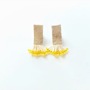 May include: A pair of gold beaded earrings with a fringe of white and yellow beads.