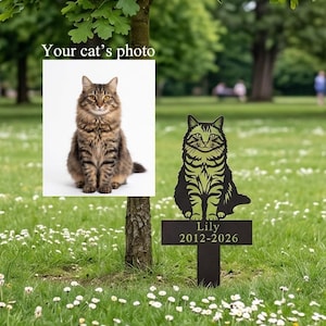 May include: A metal garden stake featuring a silhouette of a seated cat with a light green finish. Below the cat, a rectangular plaque displays the name Lily and the years 2012-2026 in a serif font. The stake is designed for outdoor placement.