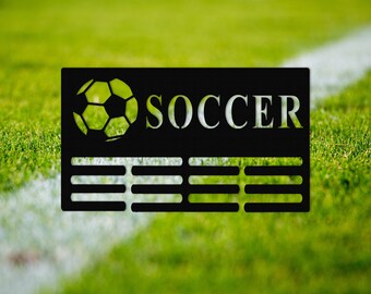 May include: Black and white sign with the word "SOCCER" in white letters and a black and white soccer ball graphic. The sign has a black background and a white border.