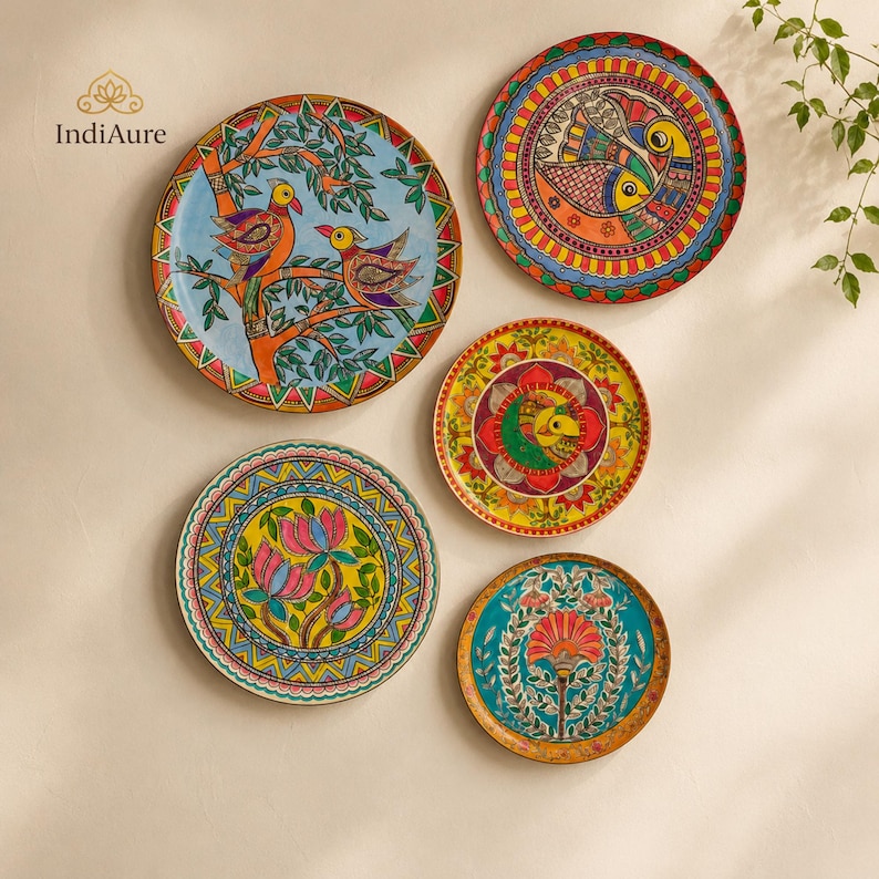 May include: Five circular decorative plates featuring vibrant hand-painted designs. One plate shows birds in a tree, another features fish, one displays a central floral motif, one shows lotus flowers, and one depicts a stylized plant with orange petals.