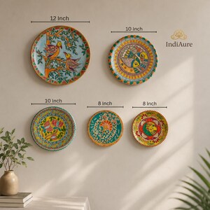 May include: Five round decorative wall plates featuring colorful hand-painted folk art designs. Sizes include one 12-inch plate, one 10-inch plate, one 10-inch plate, and two 8-inch plates. The artwork displays birds, fish, and floral motifs.
