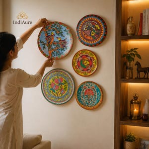 May include: Five circular decorative wall plates featuring vibrant hand-painted designs. The plates display colorful patterns including birds on branches, floral motifs, and geometric borders in shades of blue, yellow, red, and green.