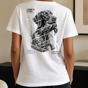 Könnte beinhalten: Ein weißes T-Shirt mit einer schwarz-weißen Grafik auf der Rückseite, die einen Deutsch Kurzhaar Hund mit einer Ente im Maul zeigt. Das Design enthält den Text BORN TO POINT, GSP DIVISION und eine Maßangabe von 24,0 IN.