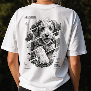 Könnte beinhalten: Ein weißes T-Shirt mit einer schwarz-weißen Grafik eines Sheepadoodle-Hundes auf der Rückseite. Das Design enthält den Text "SHEEPADOODLE", "FLUFF. LOYAL. ADVENTUROUS.", "DOODLE DIVISION", "OGD-07" und Koordinaten "37.7749 N 122.4194 W" mit geometrischen Linien.