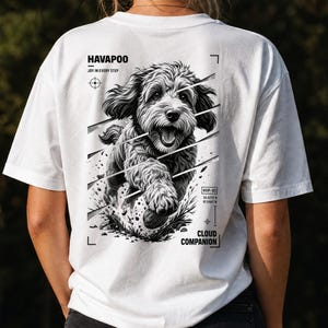 May include: A white t-shirt featuring a black and white graphic on the back of a running Havapoo dog. The text reads HAVAPOO, JOY IN EVERY STEP, HVP-01, and CLOUD COMPANION, accompanied by geometric lines and crosshair symbols surrounding the illustration.