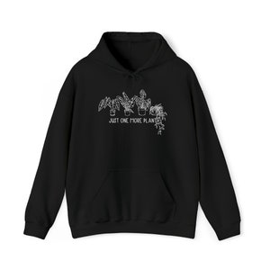 Könnte beinhalten: Ein schwarzer Kapuzenpullover mit einer weißen Linienzeichnung von vier Topfpflanzen in einer Reihe. Unter den Pflanzen ist der Text "JUST ONE MORE PLANT" in einer einfachen, klaren weißen Schrift gedruckt. Der Hoodie verfügt über eine Kängurutasche.