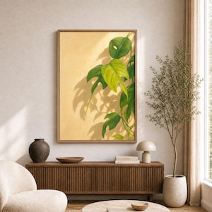 May include: A framed vertical wall art print featuring a painting of green monstera leaves against a warm, light yellow background. The artwork displays detailed foliage with natural shadows, encased in a simple, light-toned wooden frame.