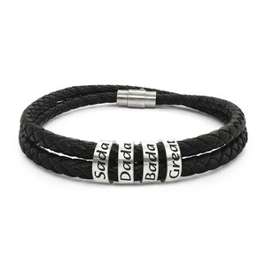 May include: A double-strand black braided bracelet featuring four cylindrical silver-toned metal beads. Each bead is engraved with black text reading Sada, Dada, Bada, and Great. The bracelet is secured with a cylindrical silver-toned magnetic clasp.