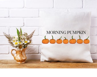 May include: White throw pillow with the text "Morning Pumpkin" printed in black. A row of eight orange pumpkins with green stems are printed across the bottom of the pillow.