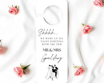 Puede incluir: Colgador de puerta blanco con un recorte circular en la parte superior. El texto negro dice: "Shhhh... WE WERE UP ALL NIGHT PARTYING WITH THE NEW MR & MRS Goulding". Una ilustración en blanco y negro de una pareja está en la parte inferior.