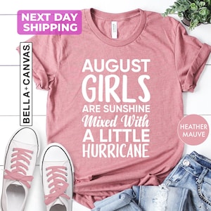 August birthday shirt featuring the phrase "August Girls Are Sunshine Mixed With a Little Hurricane" in bold white typography. Birthday graphic tee for August-born women, sisters, daughters, moms, and friends celebrating their birth month.