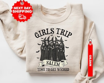 May include: Sand-colored sweatshirt with the text "GIRLS TRIP SALEM TIME TO GET WICKED" and a graphic of five witches. The sweatshirt has a crew neck and long sleeves. Small bats are scattered around the graphic.