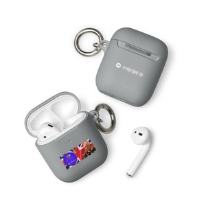 Puede incluir: Una funda de silicona gris para Apple AirPods con un accesorio de llavero. La funda tiene una pequeña pegatina con un código QR y el texto "spotify" en ella. La funda está abierta y muestra un AirPod blanco en su interior. Se muestra un segundo AirPod blanco por separado.