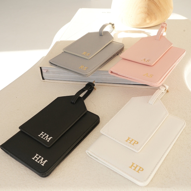 May include: Four sets of luggage tags with personalised initials. Each set includes a larger tag with a loop for attaching to luggage and a smaller tag that can be used as a passport holder. The tags are available in grey, pink, black, and white.