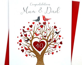 Peut inclure: Une carte blanche avec une bordure rouge. La carte représente un arbre doré avec des cœurs rouges et des oiseaux. Le texte sur la carte est "Félicitations Maman et Papa Pour votre Anniversaire de mariage de Rubis". Le nombre 40 est dans un cœur rouge sur l'arbre.