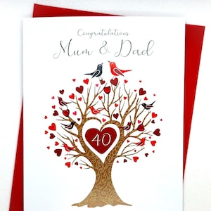 May include: A white card with a red border. The card features a gold tree with red hearts and birds. The text on the card reads "Congratulations Mum & Dad On your Ruby Wedding Anniversary". The number 40 is in a red heart on the tree.