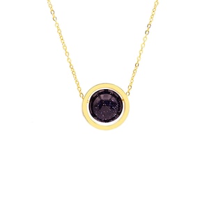 May include: A gold chain necklace with a round pendant featuring a dark blue stone surrounded by a gold circle.