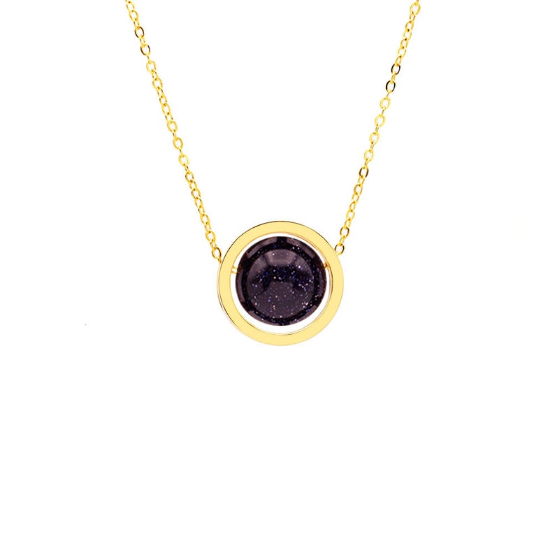 May include: A gold chain necklace with a round pendant featuring a dark blue stone surrounded by a gold circle.