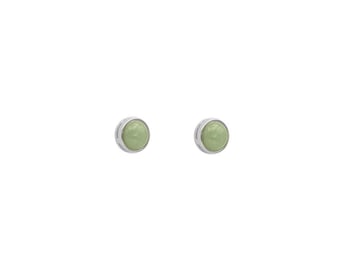 May include: A pair of silver stud earrings with a light green stone in the centre of each earring.