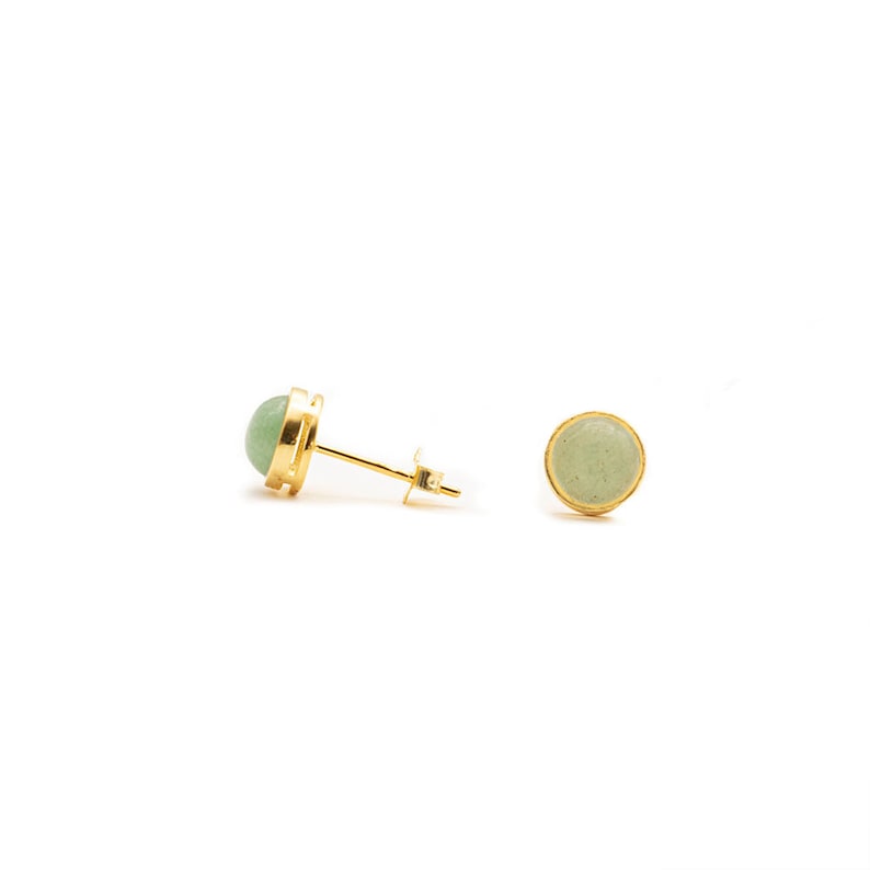May include: A pair of gold stud earrings with a light green stone in each. The earrings are simple and elegant.