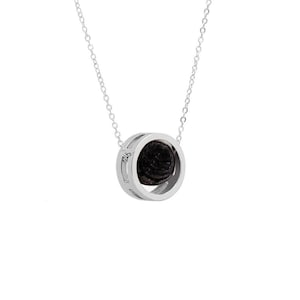 May include: A silver chain necklace with a round pendant featuring a black stone set in a silver frame.