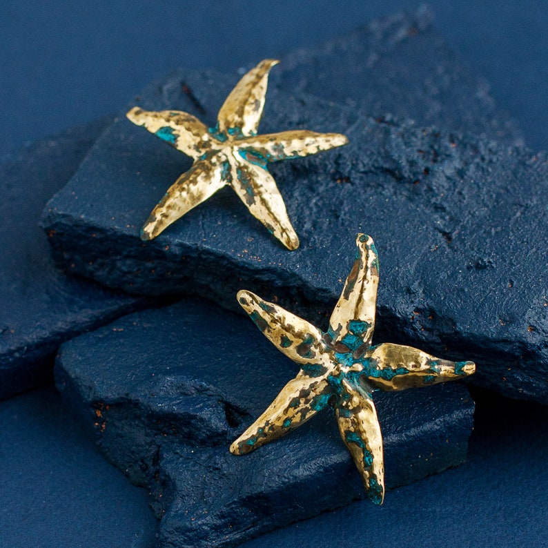 Big starfish earrings made of golden metal and blue patina. Earrings are artisan made, each pair is different. Earrings are polished, the majority of their surface is golden, patina is only in hollows.