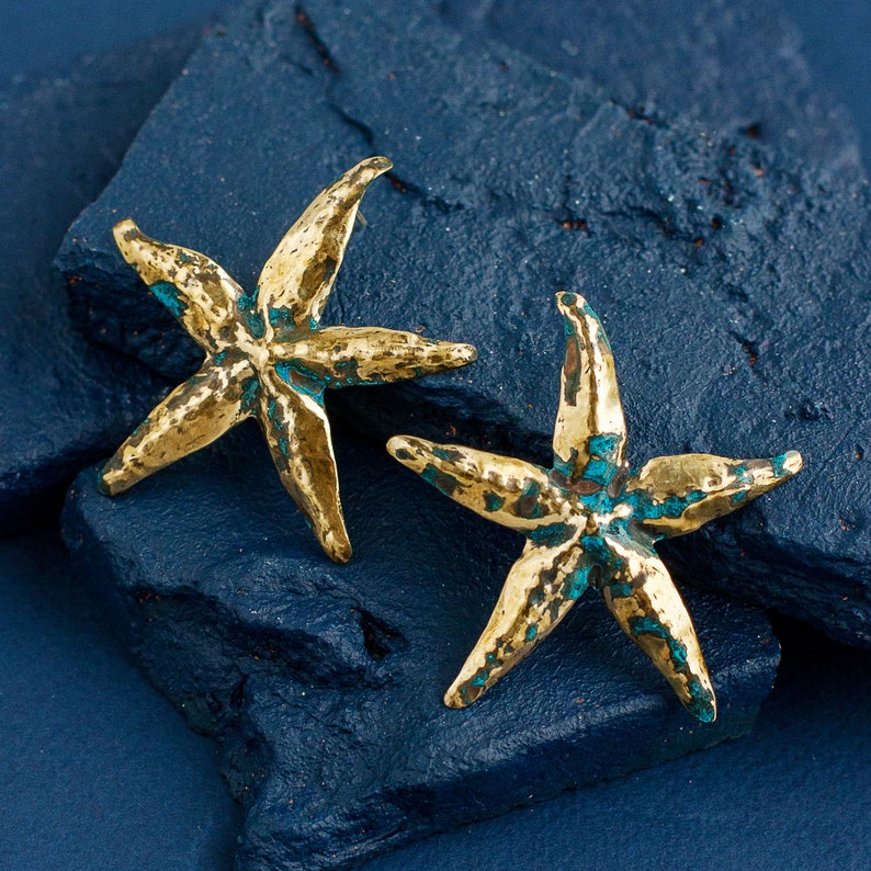 Shiny brass stud earrings in the shape of starfish. Earrings are not flat, they have curves and hollows as they are handmade with hammer and other tools.