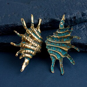 Bolg earrings in the form of long ribbed shells with spikes of different length on one side. Earrings are a bit mismatched due to their artisan nature. Photo shows them from front and back side, it is seen that brass has blue patina in hollows.