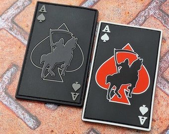 May include: Two black playing cards with a black and white image of a rider on a horse with a scythe. The cards are the Ace of Spades and feature the text "A" and a spade symbol.