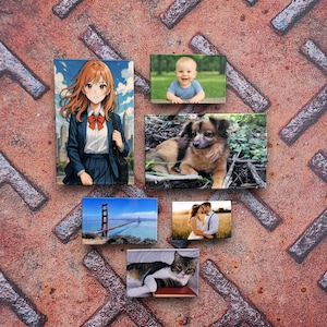 Puede incluir: Una colección de impresiones fotográficas rectangulares con varias imágenes. Las impresiones incluyen un personaje de anime, un bebé, un perro, el puente Golden Gate, una pareja y un gato. El fondo es una superficie metálica oxidada y texturizada.