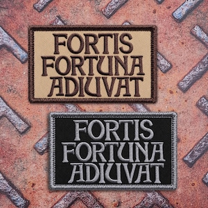 May include: Two rectangular embroidered patches featuring the Latin phrase FORTIS FORTUNA ADIUVAT. One patch has a tan background with dark brown lettering and border, while the other has a black background with light gray lettering and border.