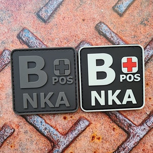 May include: Two black and white patches with the letter B and a red plus sign with the text POS and NKA.