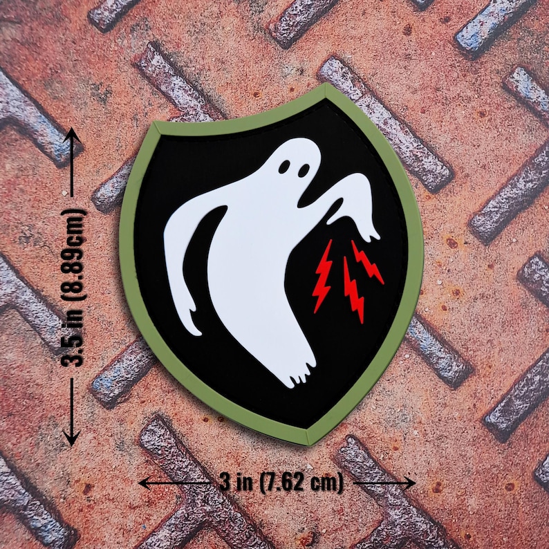 Op de afbeelding: Een schildvormige patch met een wit spookontwerp en rode bliksemschichten op een zwarte achtergrond, omlijst door een groene rand. De patch is 8,89 cm hoog en 7,62 cm breed.