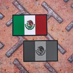 Könnte beinhalten: Zwei rechteckige Aufnäher mit der mexikanischen Flagge. Der obere Aufnäher zeigt die Flagge in ihren traditionellen Farben: Grün, Weiß und Rot, mit dem Wappen in der Mitte. Der untere Aufnäher ist in Grautönen gehalten, mit dem Wappen.