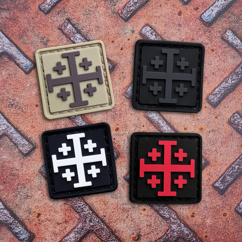 May include: Four square patches featuring the Jerusalem cross design. The patches are in various color combinations: tan and brown, black and gray, black and white, and black and red. The patches are on a rusty metal surface.