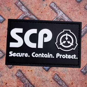 Può includere: Toppa rettangolare nera con testo e simbolo bianchi. Il testo recita "SCP Secure. Contain. Protect." Il simbolo è un cerchio con tre frecce rivolte verso l'interno. La toppa ha un bordo nero.