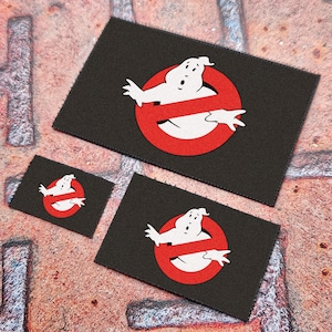 Könnte beinhalten: Drei schwarze Stoff-Patches mit einem weißen Geist und einem roten 'Kein Geist'-Symbol. Die Patches sind in verschiedenen Größen.